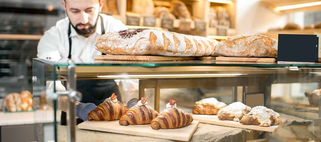 Seller putting croissants in the store showcase of the bakery.