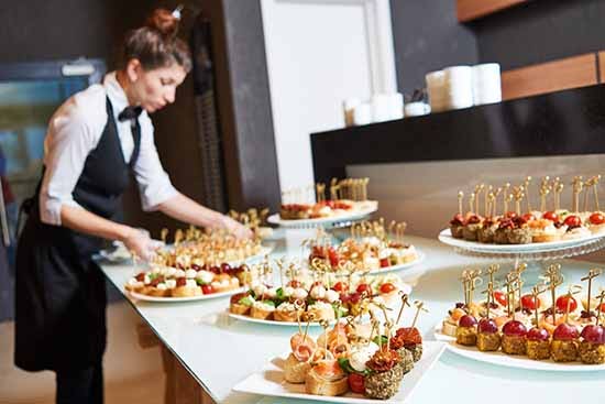 Catering server arranging food for a buffet.