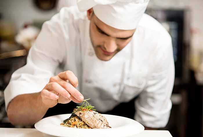 Catering chef plating food before service.