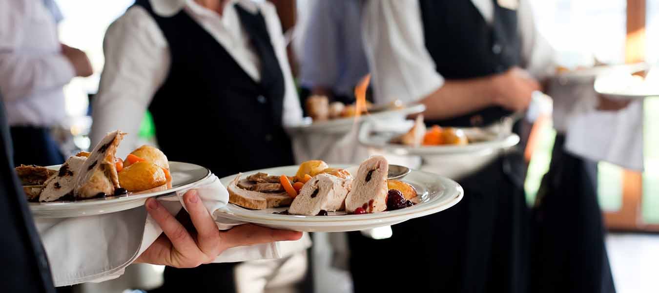 Waiters carrying plates with meat dish at a wedding.