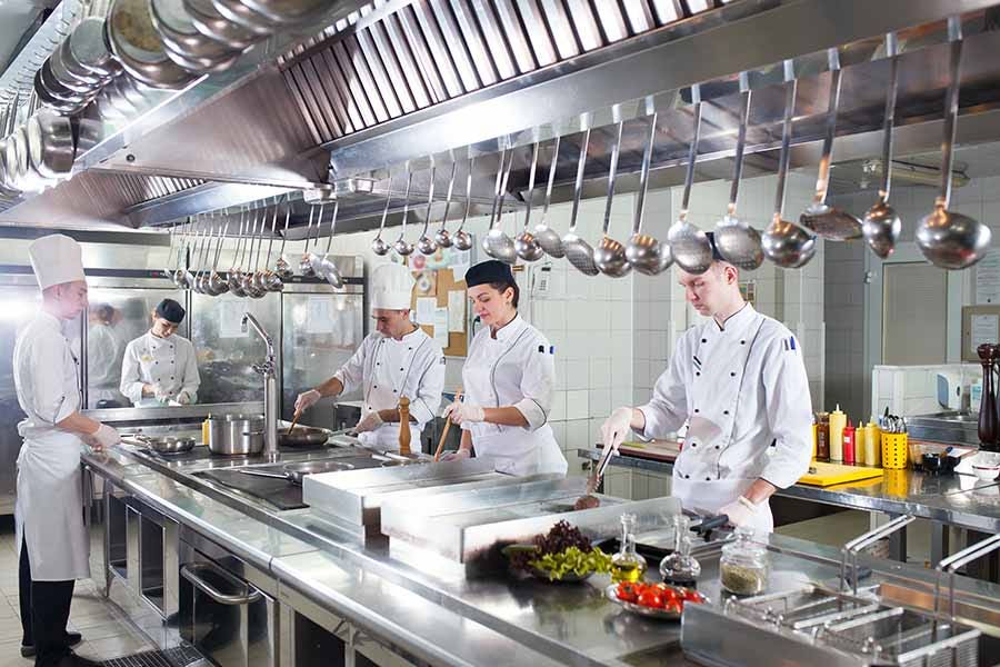 Cooks work in a commercial kitchen at a restaurant.