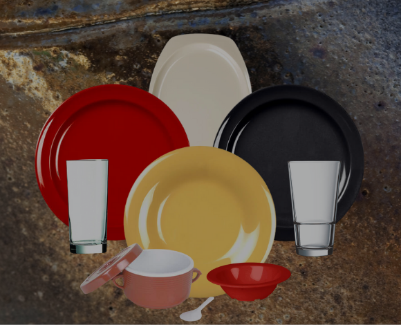 Three plate, one red, one yellow and one black with a white platter, two glasses, a red bowl and a pink crock with a lid all on a stone background.