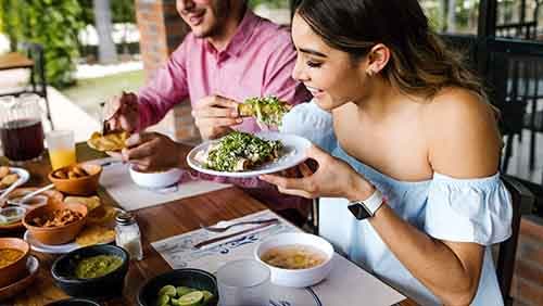 young latin woman eating mexican tacos on a restaurant terrace in Mexico Latin America