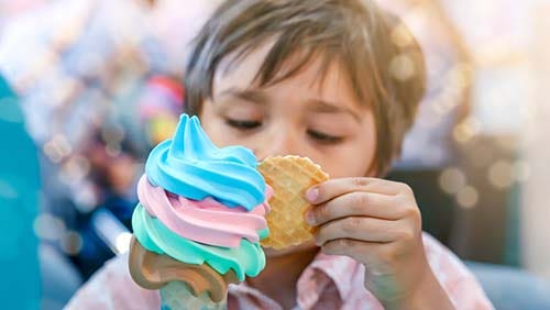 Close-up of a man scooping ice cream from tub in an ice cream parlor.