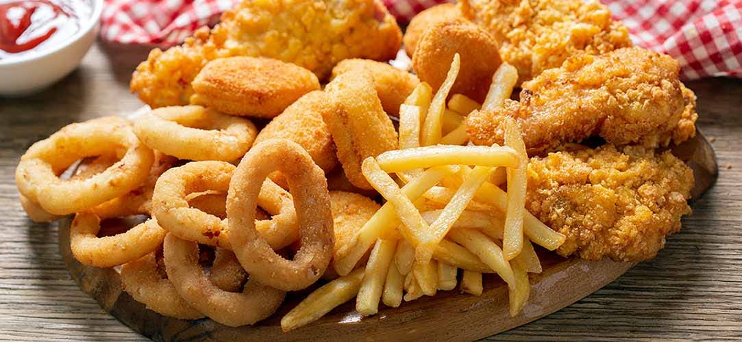 onion rings, french fries, chicken nuggets and fried chicken on a wooden table