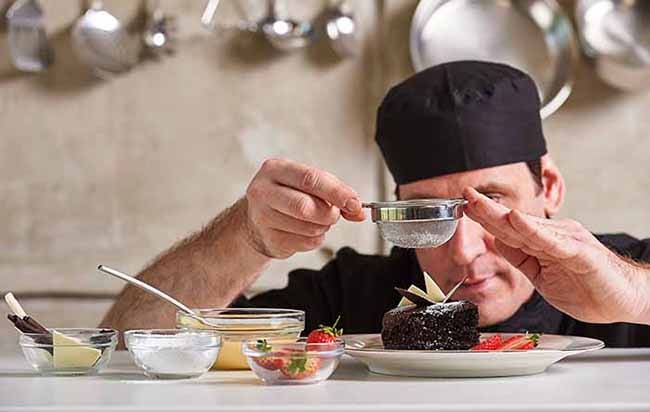 Restaurant hotel private chef finishing plating of chocolate cake.