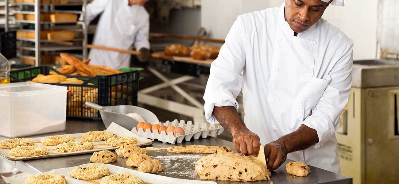 Baker at work making sweet buns with dough and eggs