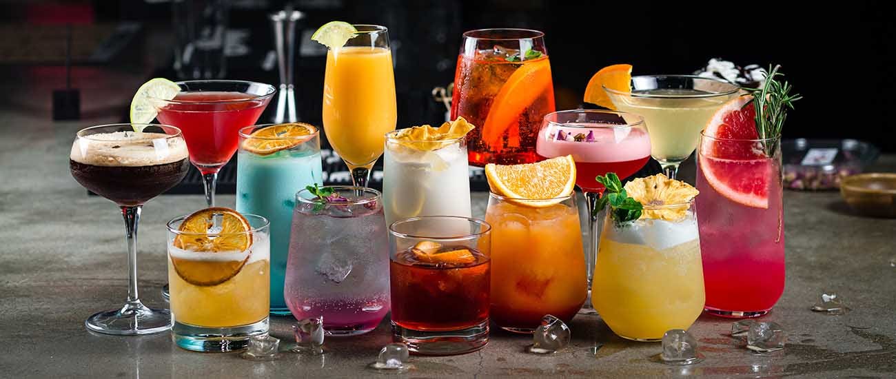 Set of alcoholic cocktails: Almond Whiskey Sour, Mango Daiquiri, Long Island, Whiskey Sour, Blue Hawaii, Pina Colada, Bramble, Daiquiri, Ruby Red Grapefruit Paloma, Aperol Syringe, Espresso Martini.