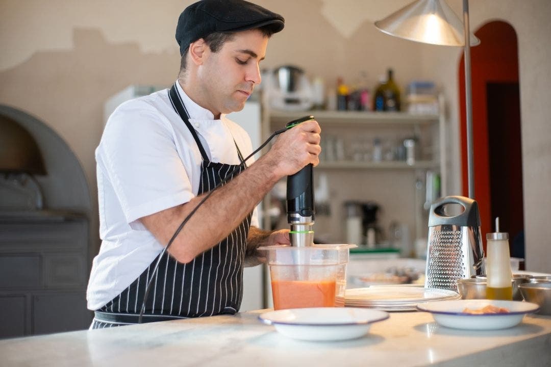 Chef blending soup with immersion blender in restaurant kitchen