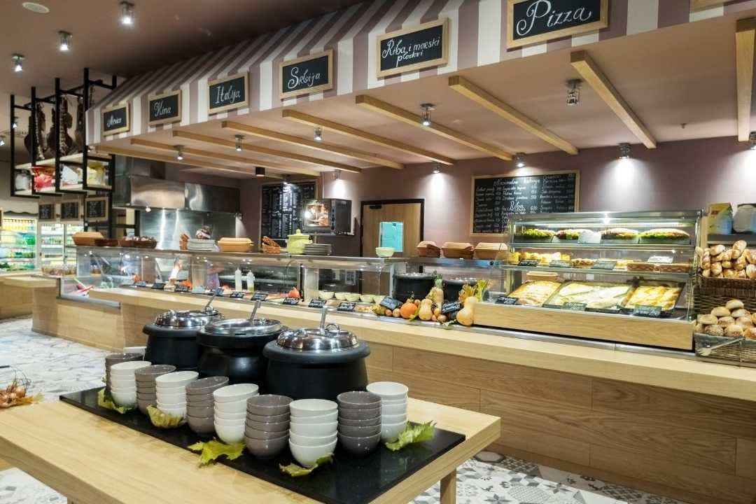 Cafeteria line – Modern cafeteria counter with soups, pizzas, and fresh baked goods on display.