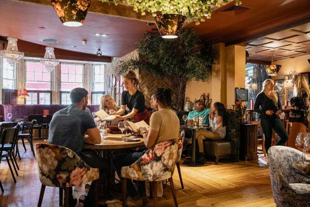 Casual dining restaurant with server taking orders and guests seated in a cozy, elegant setting.
