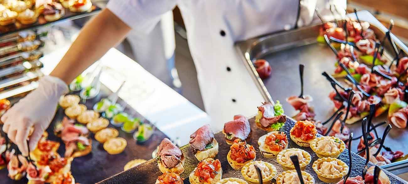 Hands of a cater in white gloves laying out sandwiches