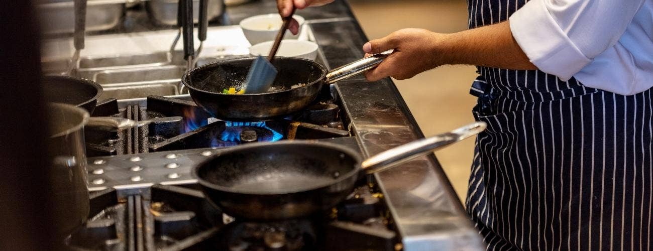 chef cooking in a saute pan on a range