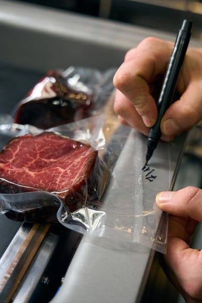 Chef writing date on a package of vacuum sealed steak.