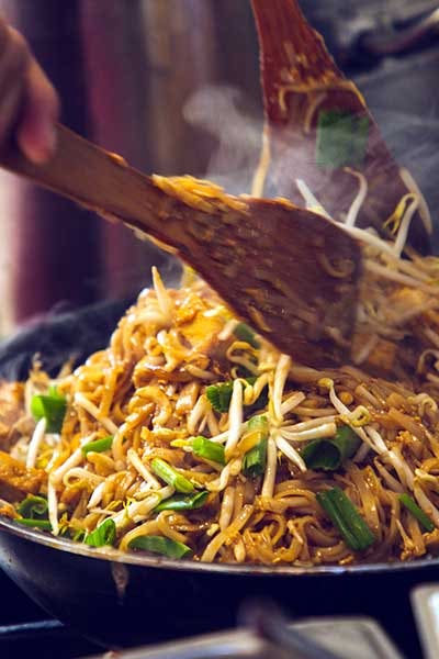 Pad Thai is Thai food Noodle and tofu mixed with tamarind sauce and bean sprouts and spring onion in a pan cooking in the restaurant.