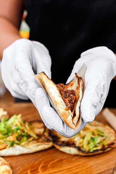 Female street vendor hands making taco outdoors.