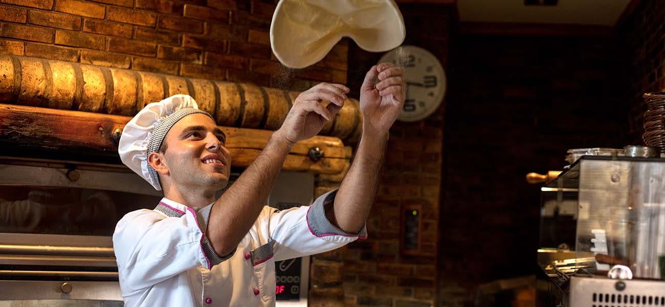 Pizza chef tossing pizza dough in the air