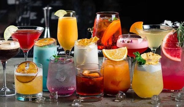 Variety of colorful cocktails with garnishes displayed on a bar counter.