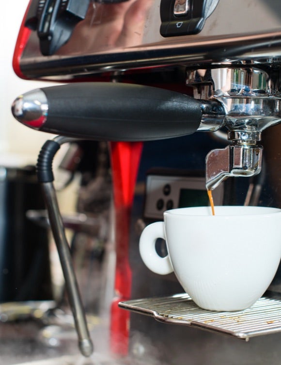 Coffee maker pours coffee into a cup.