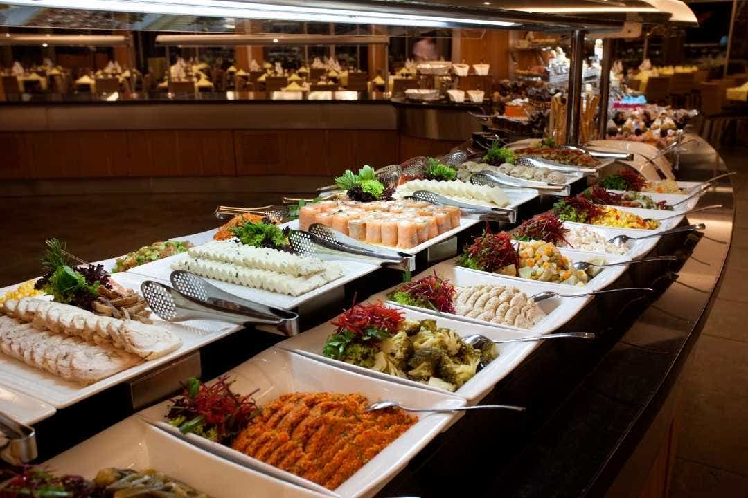 Self-serve buffet with assorted cold dishes in a commercial foodservice setup.