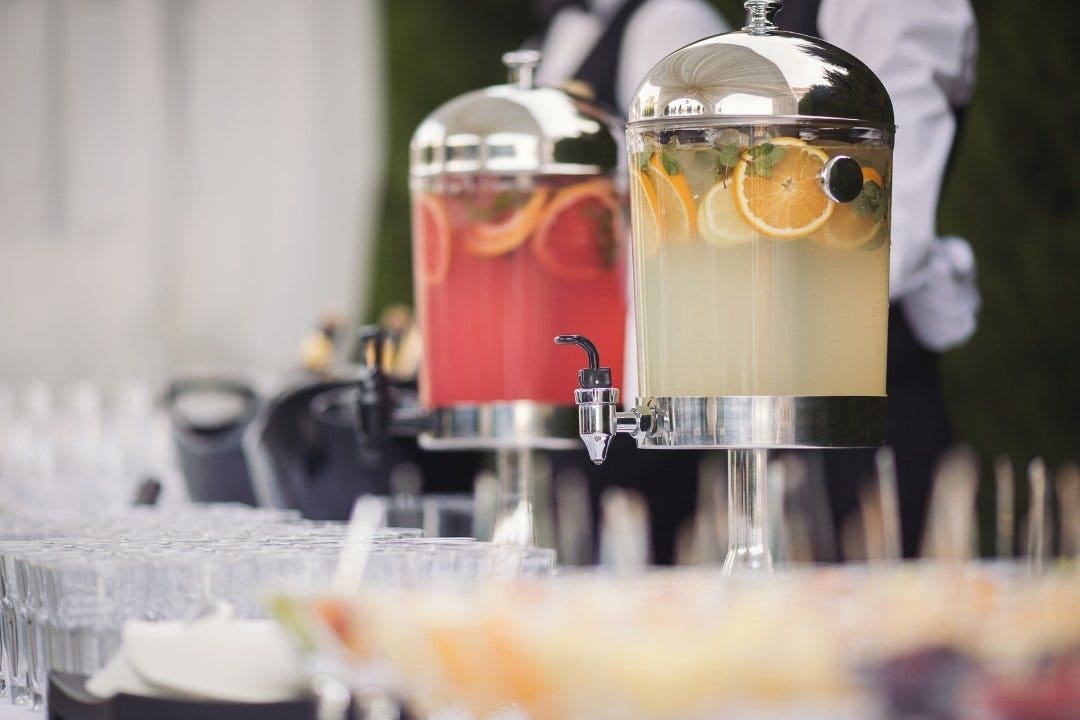 Cold beverage dispensers with fruit-infused drinks at a formal catered event.