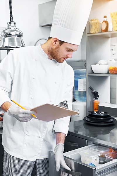 A chef opens the drawer to an undercounter refrigerator to check ingredients before service begins.