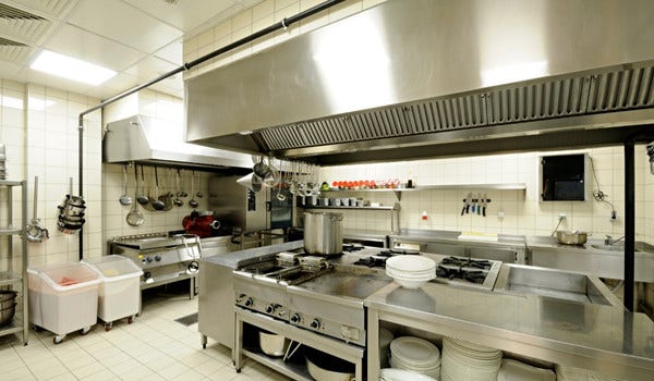 Commercial restaurant kitchen showing a flat top, plates, burners, pots, pans, and more.
