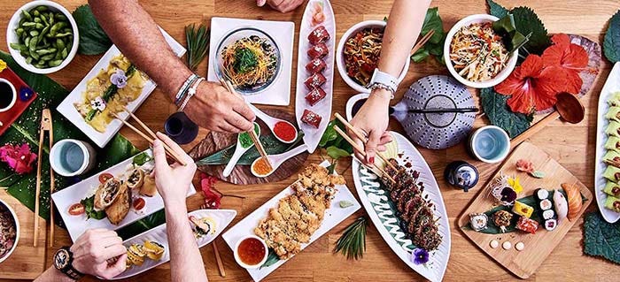 Friends sharing asian food and eating with chopsticks