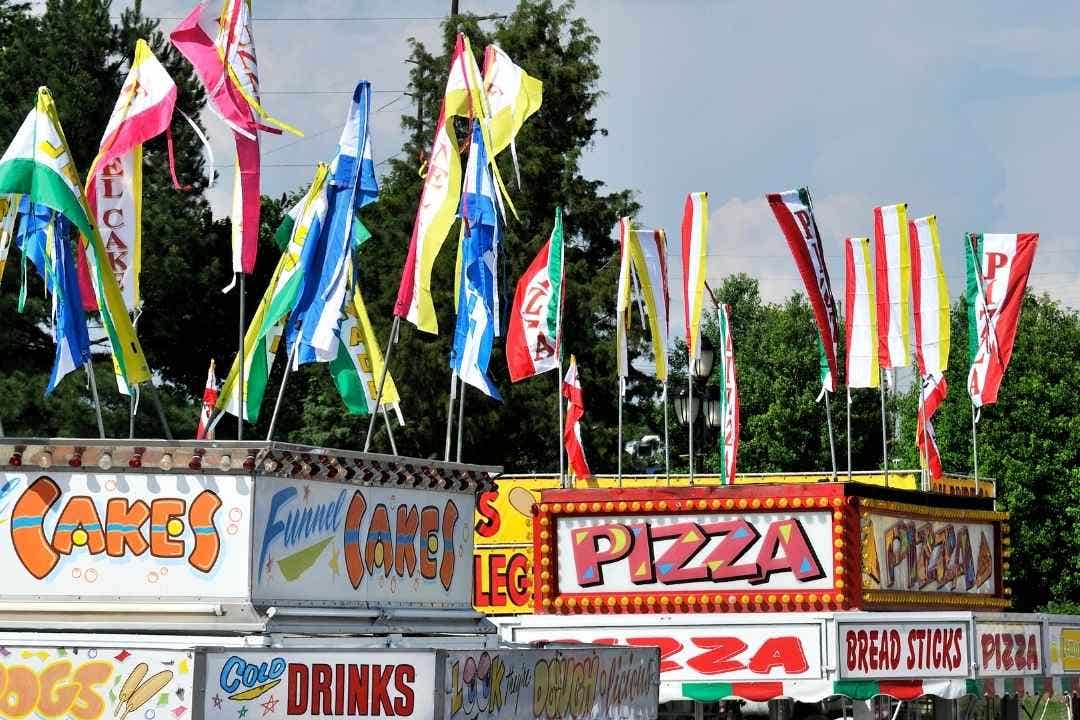 Concession stand – Colorful concession stands with flags advertising pizza and funnel cakes.