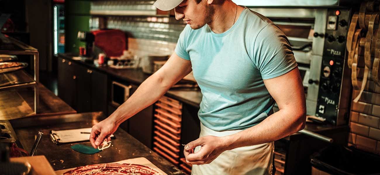 Man making a pizza in pizzeria kitchen.