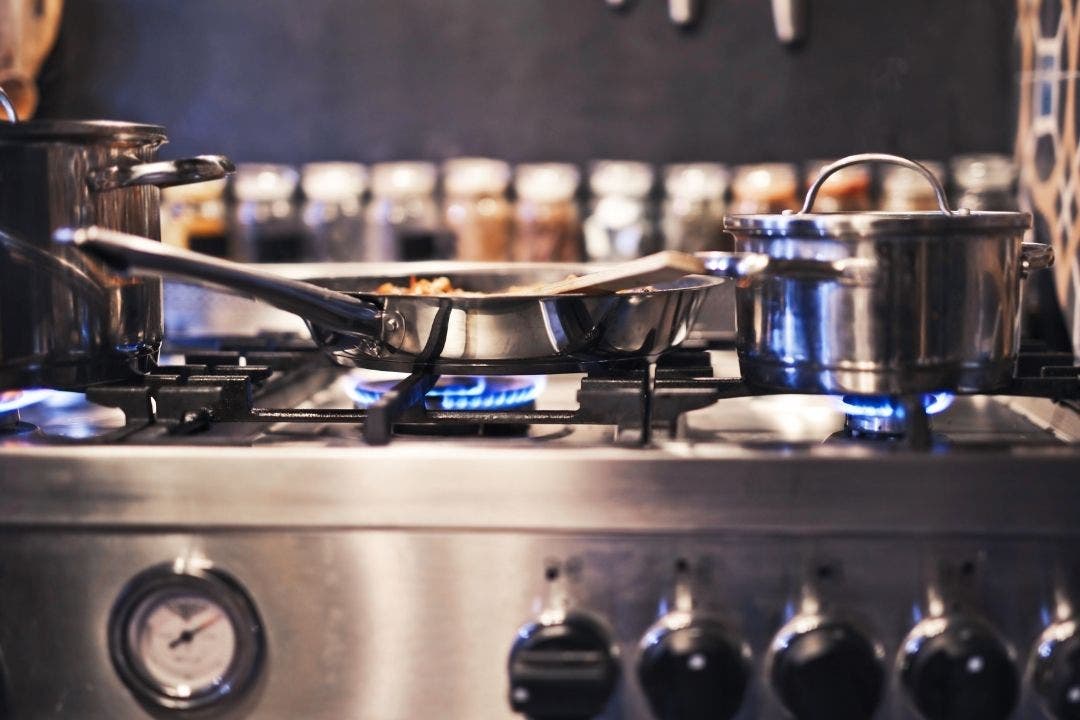 Stainless steel pots and pans cooking on commercial gas stove