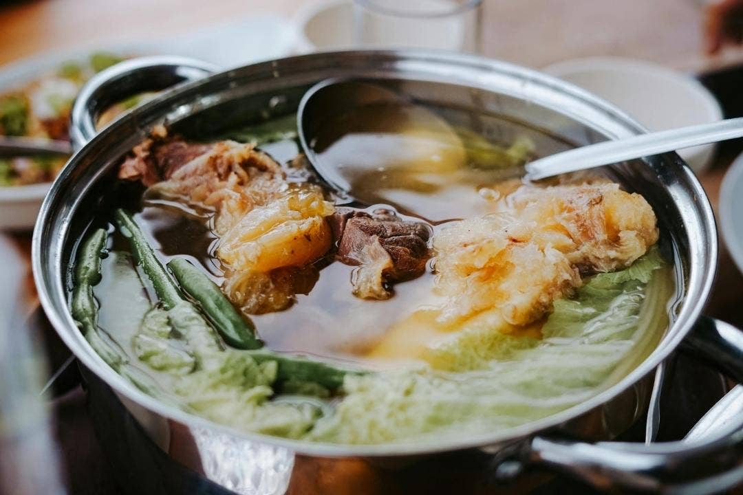 Beef and vegetable soup simmering in a stainless steel pot
