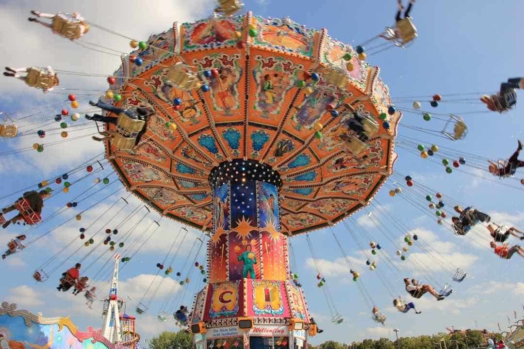 Colorful swing ride spinning at a lively carnival under a blue sky