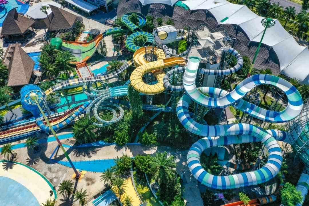 Aerial view of a vibrant water park with twisty slides and tropical scenery