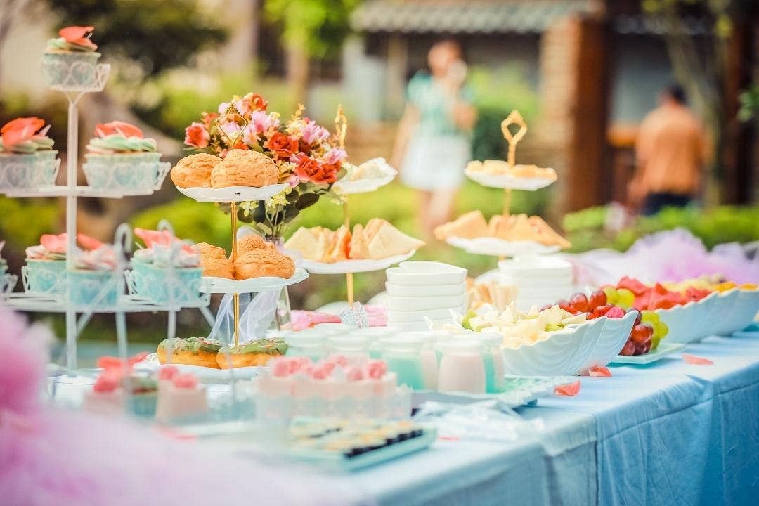 Elegant outdoor party table with cupcakes, sandwiches, and floral decorations