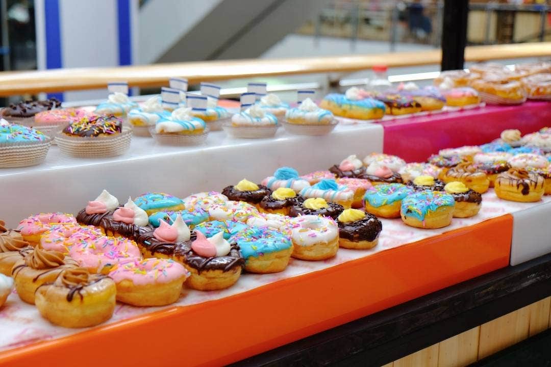 Assorted colorful frosted donuts on display in a sweet shop or bakery