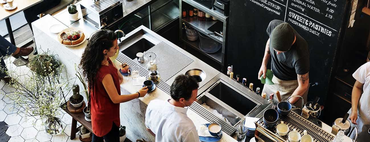 Customers wait for orders at the counter of a coffee shop.