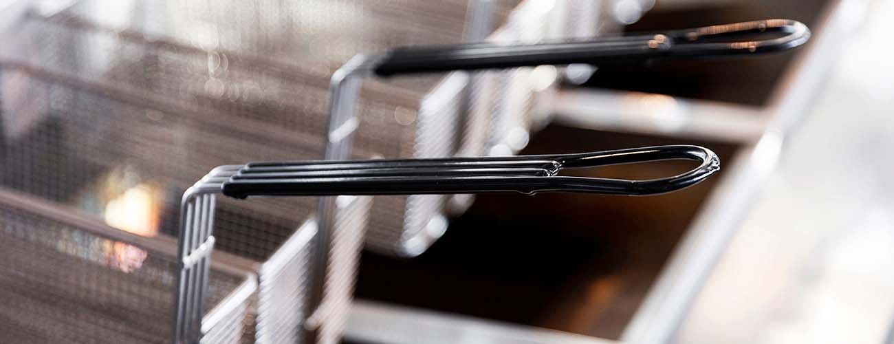 Stainless steel frying baskets in commercial kitchen.