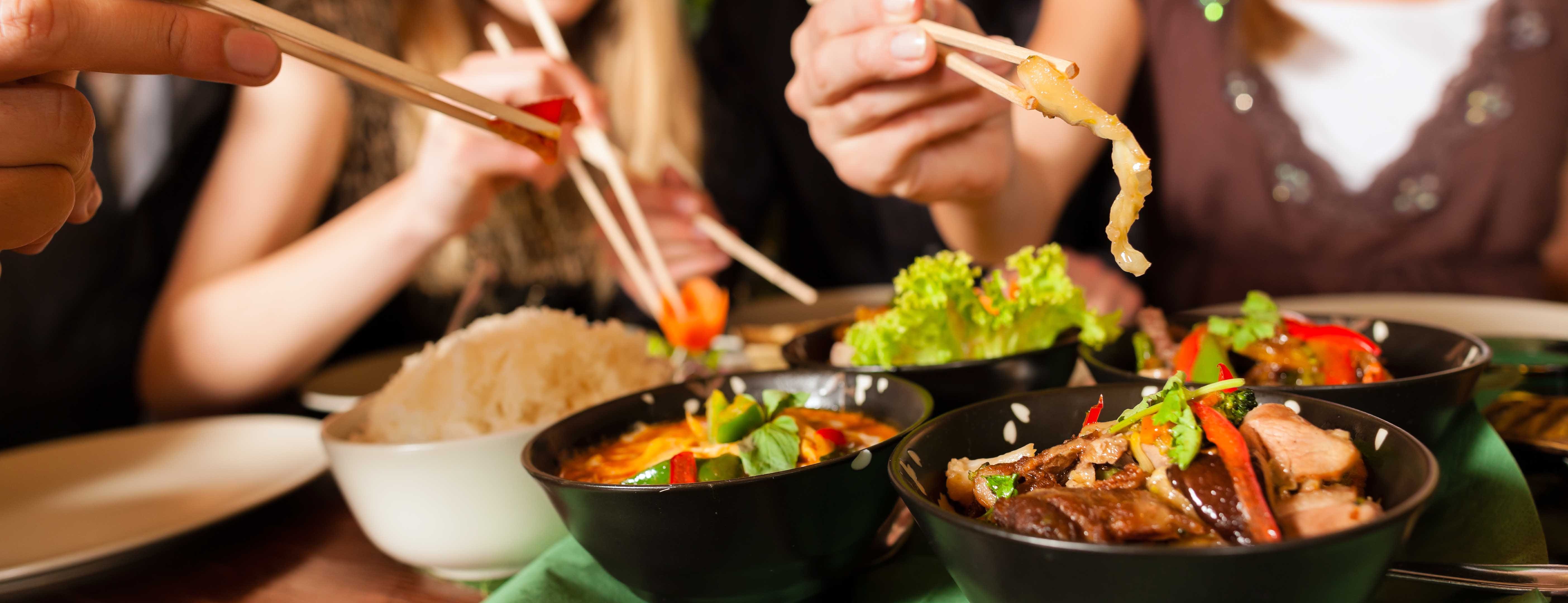 Young people eating with chopsticks in a Thai restaurant.