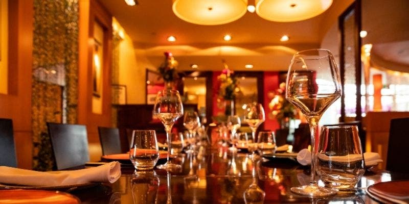 Fancy restaurant dining room with water and wine glasses in a dimly lit room. 