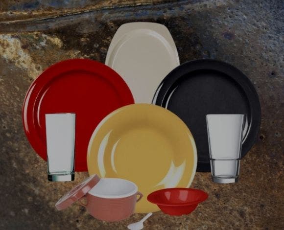 Three plate, one red, one yellow and one black with a white platter, two glasses, a red bowl and a pink crock with a lid all on a stone background.