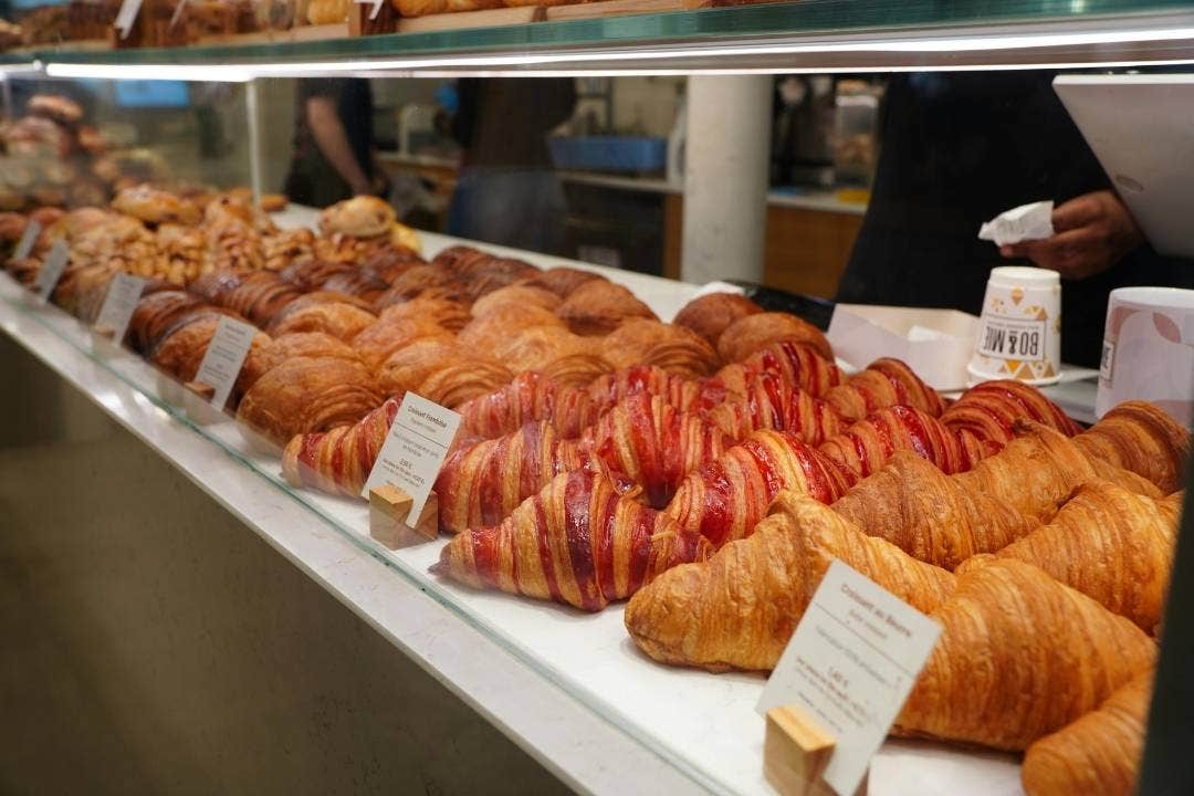 Bakery case filled with fresh croissants and pastries in a modern glass display.