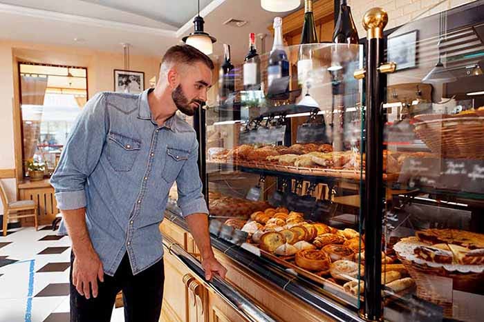 Male customer shopping at local coffee shop bakery display.
