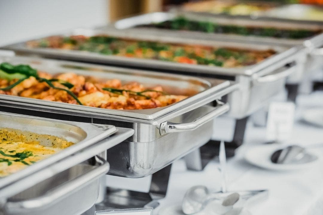 Buffet steam table with stainless steel pans holding hot entrees and sides