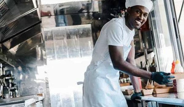 Smiling chef preparing food in a modern food truck kitchen.