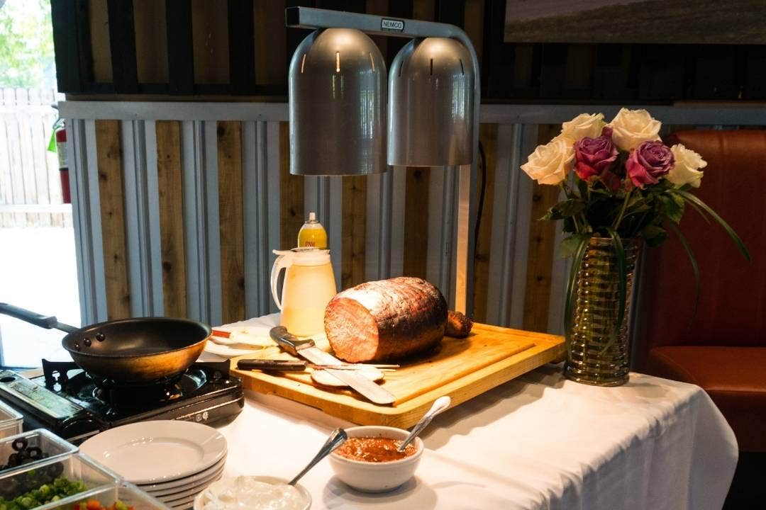 Carved roast beef under heat lamp on carving station with utensils and serving setup