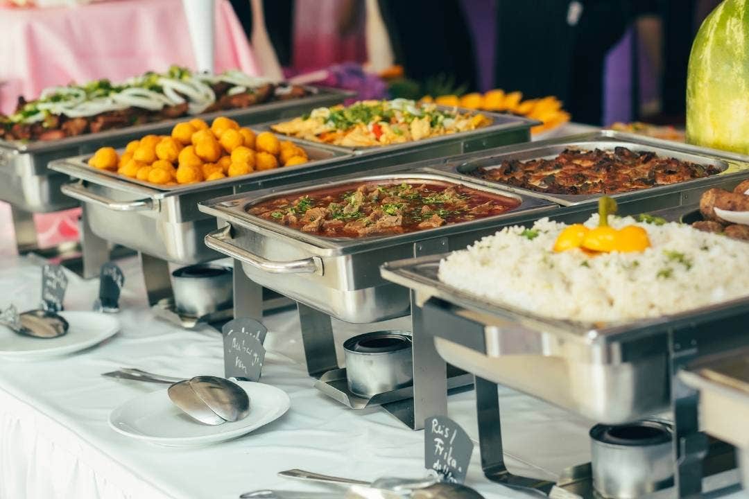 Buffet line with chafing dishes holding rice, stews, and appetizers for food service