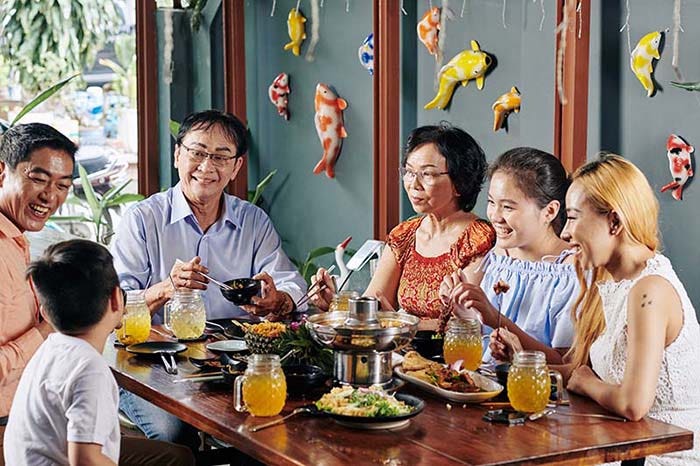 Happy Asian family talking, laughing and eating good food at dinner in an Asian restaurant.