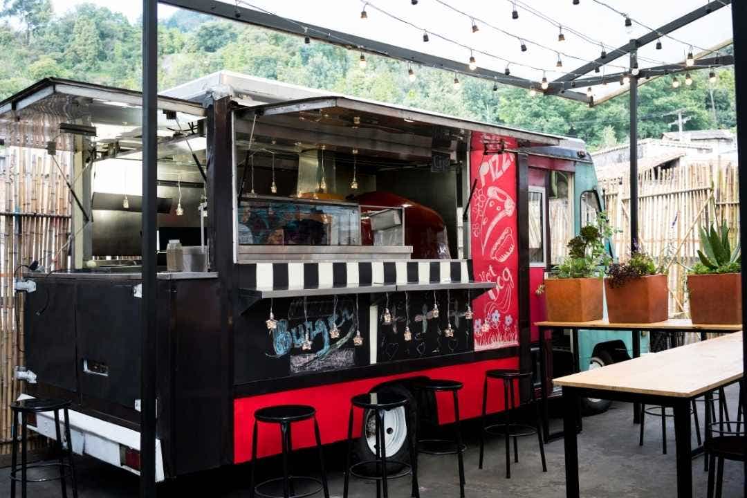 Food truck with bar stools under string lights in an outdoor patio setting
