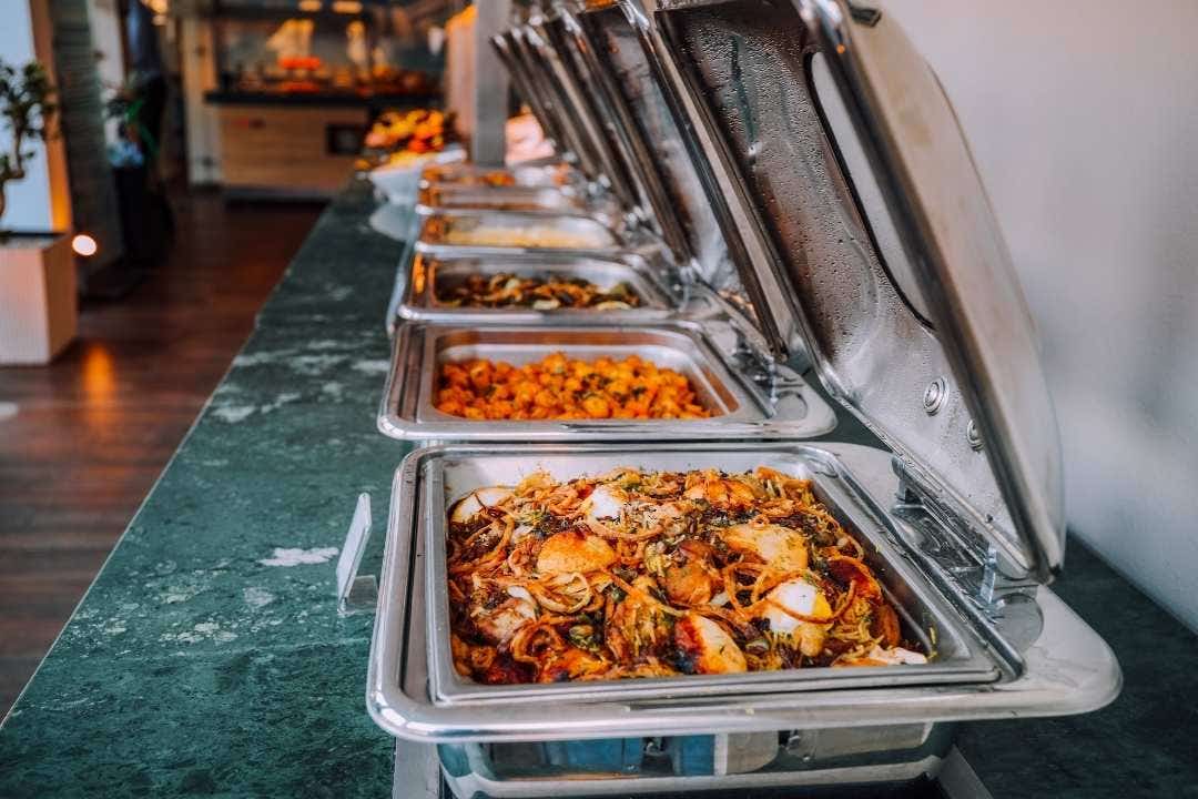 Buffet line with stainless steel chafing dishes filled with assorted hot foods